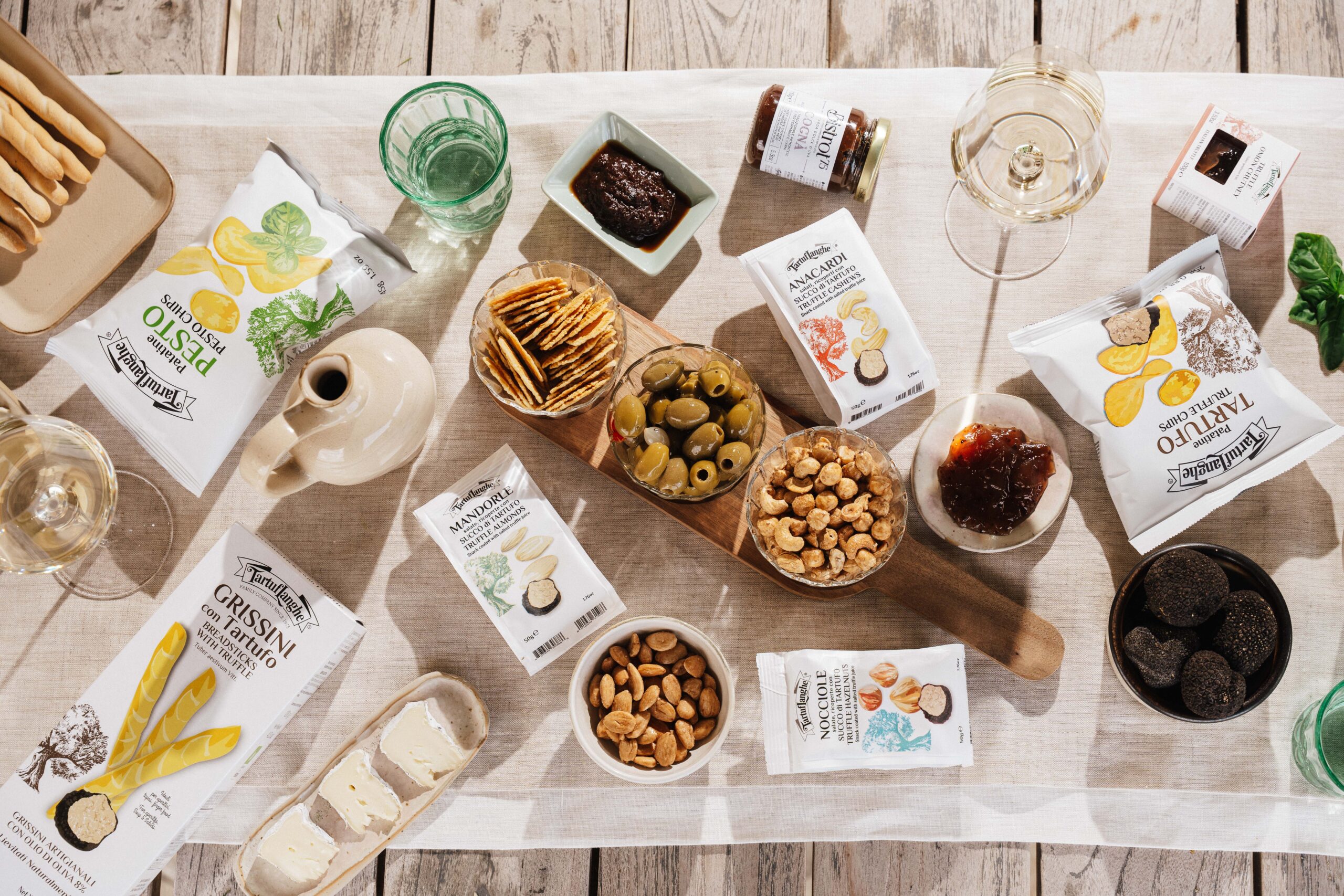 Aperitivo Tartuflanghe con snack al tartufo, olive, frutta secca, formaggi, confetture e calici di vino.